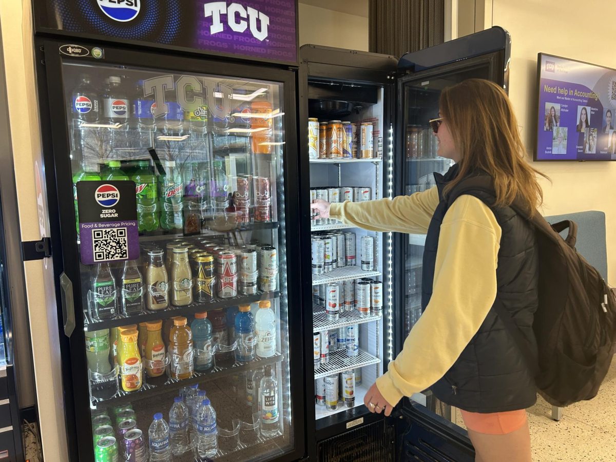 A TCU student reaches for a Celsius from a vending machine- a refreshing boost amidst a hectic day of lectures and exams. (Kelsey Finley/Staff Writer)