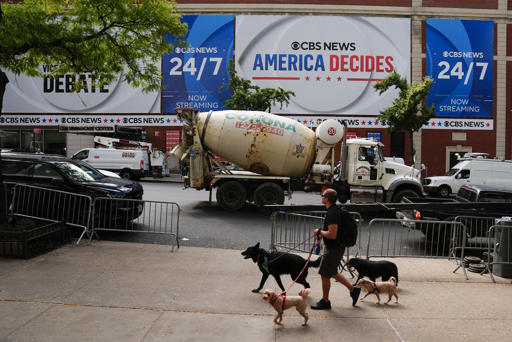 A person walks dogs a day ahead of a CBS News vice presidential debate between Republican vice presidential nominee Sen. JD Vance, R-Ohio, and Democratic vice presidential nominee Minnesota Gov. Tim Walz, in New York., Monday, Sept. 30, 2024. (AP Photo/Matt Rourke)