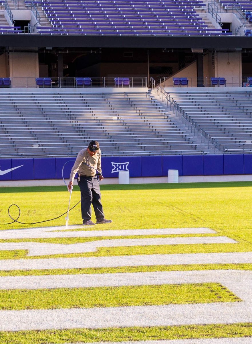 A TCU groundskeeper fills in lettering in the end-zone of Amon G. Carter Stadium.