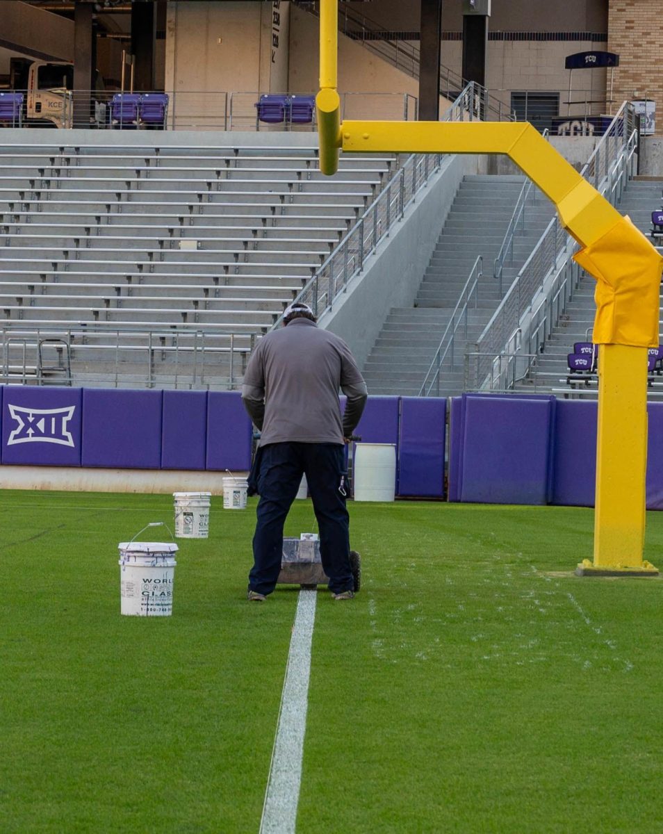 A TCU groundskeeper paints lines on the field at Amon G. Carter Stadium.