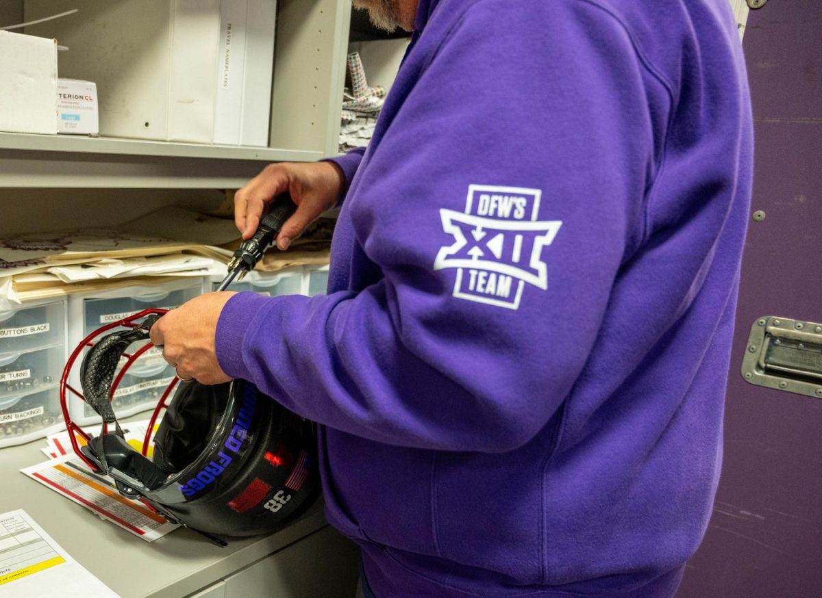 A TCU equipment manager tightens the screws on a helmet.