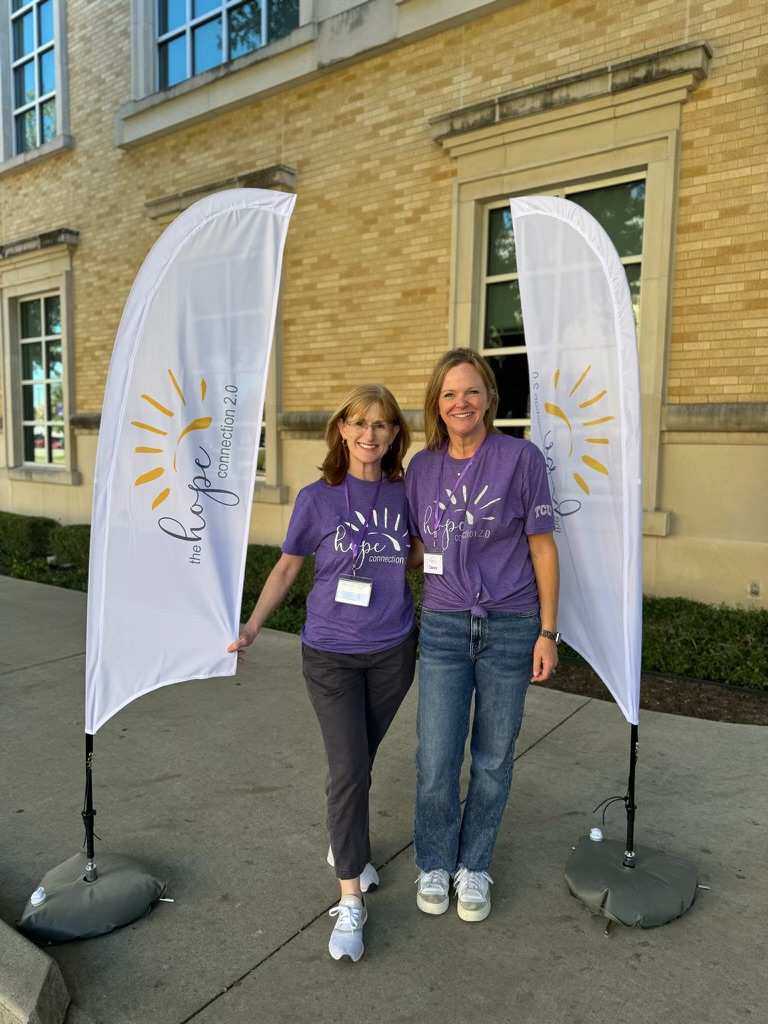 Dr. Danica Knight (left) and Dr. Casey Call (right) place Hope Connection 2.0 banners outside Rees-Jones Hall to welcome families to camp.