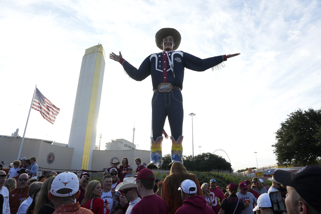 Football fans mill around Big Tex before heading to see an NCAA college football game between Oklahoma and Texas at the Cotton Bowl in Dallas, Saturday, Oct. 7, 2023. (AP Photo/LM Otero)