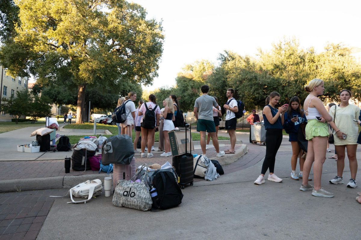 Residents of Colby Hall standing outside the dorm with bags of belongings after a pipe burst in the building.