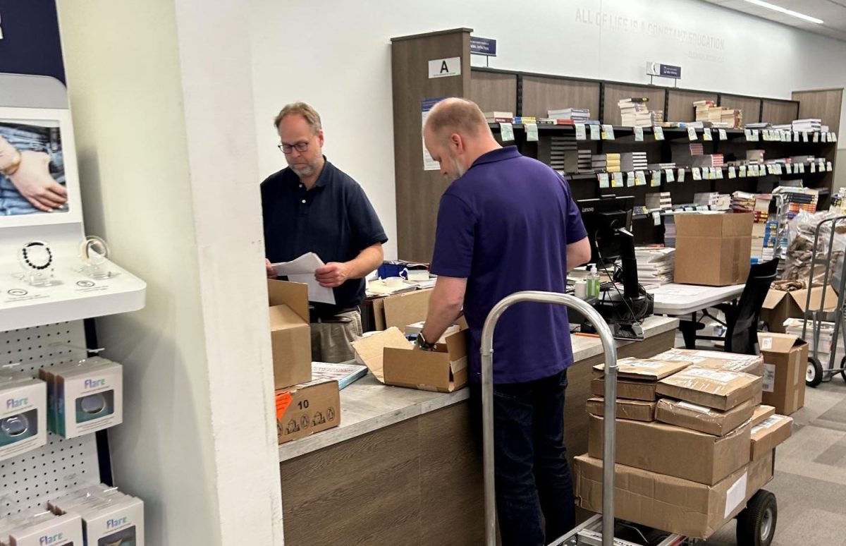 TCU Bookstore manager and tech associate going through textbooks. (Grace Lewis/Staff Writer)