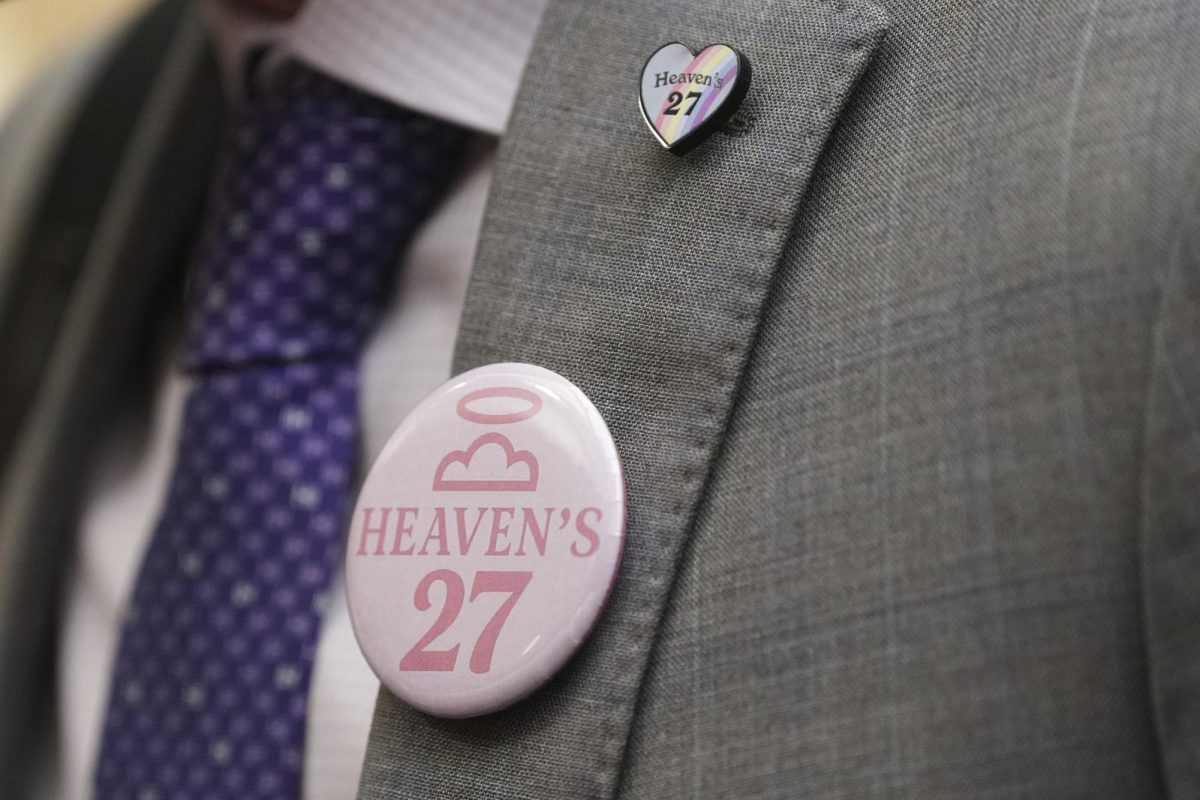 The parent of a child lost to the recent flooding in Kerr County wears a 'Heaven's 27' button during a Texas Senate hearing at the Texas Capitol, Wednesday, Aug. 20, 2025, in Austin, Texas. (AP Photo/Eric Gay)