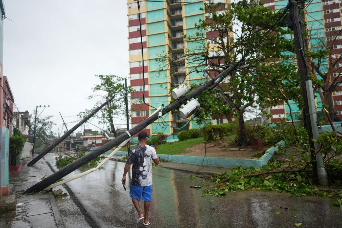 A man takes pictures of fallen electrical posts on the street in the aftermath of Hurricane Melissa in Santiago, Cuba, October 29, 2025. REUTERS/Alexandre Meneghini