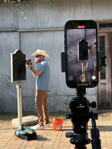 Chris Woolsey sands down a historical marker in Gruene, Texas, before painting on Oct. 27, 2025.